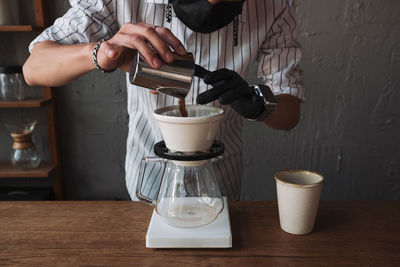 Man pouring coffee in cup on table