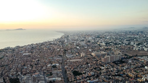 High angle view of townscape by sea against sky during sunset