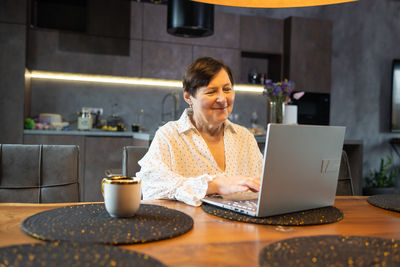 Senior woman using laptop in kitchen