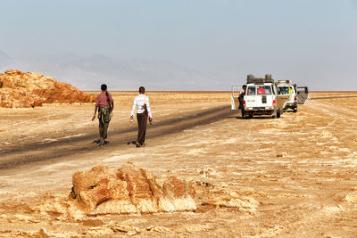 Rear view of people on desert against sky