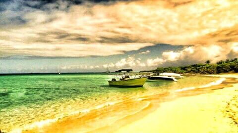 Boats in calm sea against cloudy sky