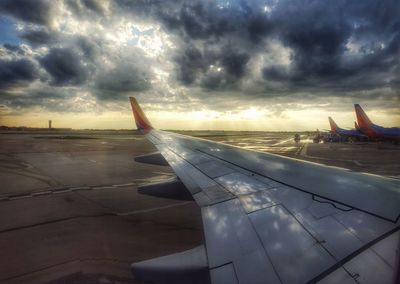 Close-up of airplane wing against sky during sunset