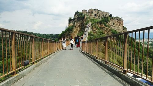 People on walkway against historic town on hill