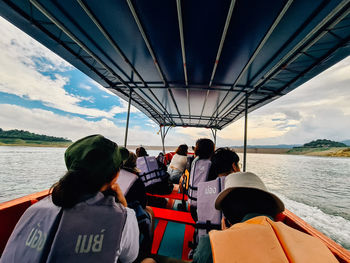 Rear view of people on boat in sea against sky