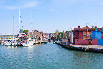 Sailboats moored on harbor by buildings in city