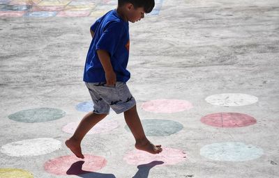 Boy jumping on colorful spots on concrete ground