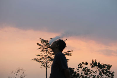 Silhouette woman standing against orange sky