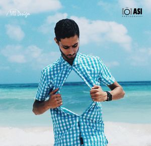 Man with umbrella standing in sea against sky