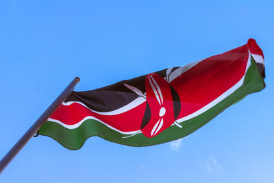 Low angle view of kenyan flag against clear blue sky