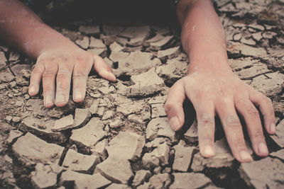 High angle view of cropped hands on barren ground