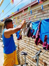 Man holding multi colored flags hanging against the wall