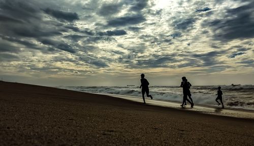 People on beach against sky during sunset