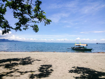 Boat moored on beach against sky