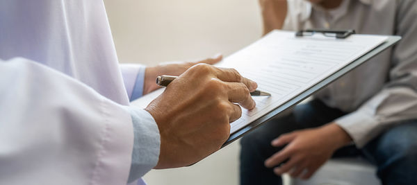 Midsection of man holding smart phone on table