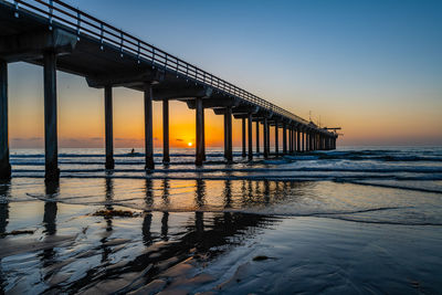 Pier over sea against sky during sunset