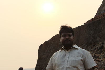 Portrait of man sitting against clear sky at sunset