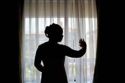 Rear view of woman standing by curtain