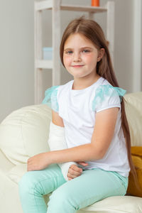 Portrait of young woman sitting on bed at home