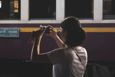 Rear view of woman standing against wall