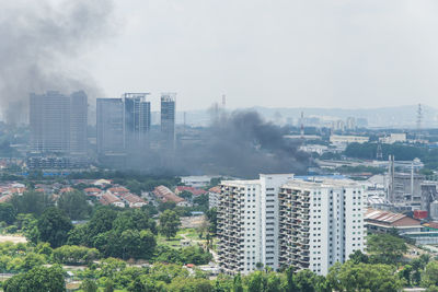 Smoke amidst cityscape against sky