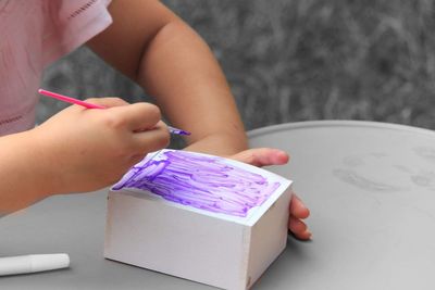 Cropped image girl painting craft at table