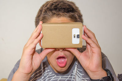 Close-up of surprised boy looking in smart phone through cardboard virtual reality simulator