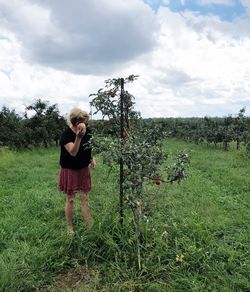 Rear view of man standing on field against sky