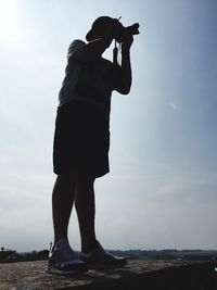 Low angle view of silhouette man photographing against sky