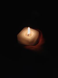 Close-up of illuminated candle over black background