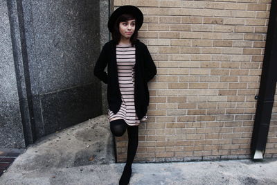 Portrait of young woman standing on wall