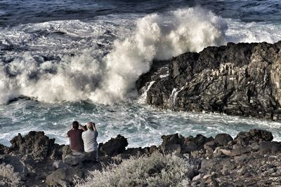 Two men photographing the ocean