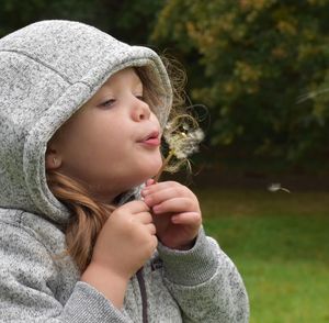 Close-up of girl blowing dandelion seeds at park