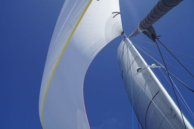 Low angle view of sailboat in sea against blue sky