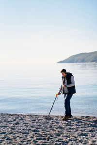 Rear view of man standing on sea against sky