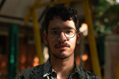 Mixed race man wears round eyeglasses under the shades and sunlight