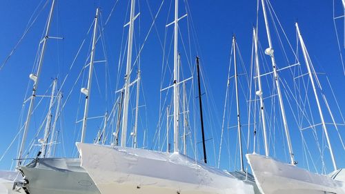 Low angle view of boats moored at harbor against clear blue sky