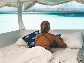 Rear view of man relaxing on bed at beach