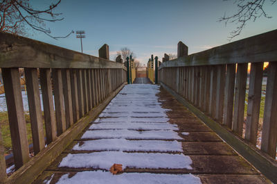 Wooden bridge in winter against sky