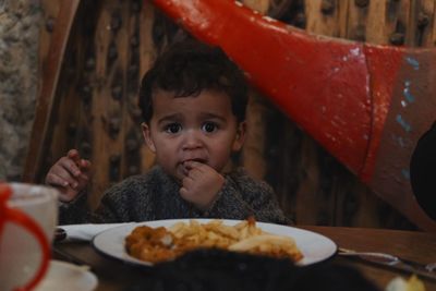 Portrait of cute baby boy eating food on table at home