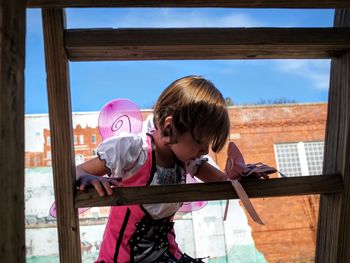 Girl in costume on wooden ladder against building