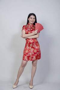 Full length portrait of young woman standing against white background