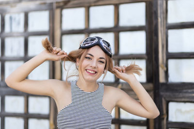 Portrait of smiling young woman with long blond hair wearing flying goggles