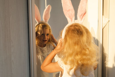 Funny cute baby girl wearing rabbit ears in front of mirror.easter holiday 