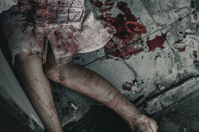 Midsection of woman with blood sitting on floor