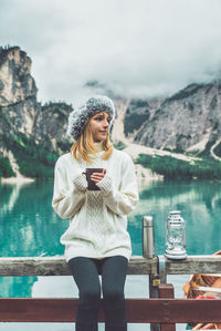 Full length of young woman using phone while standing on mountain