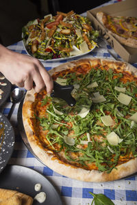 Girl cut pizza on the table close up. vertical image