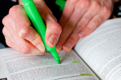 Cropped image of woman highlighting in book at home