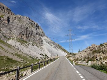 Empty road by mountains against sky