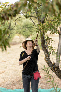 Portrait of a female farmer harvesting almonds by hand.