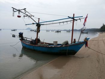 Fishing boat moored in sea against sky